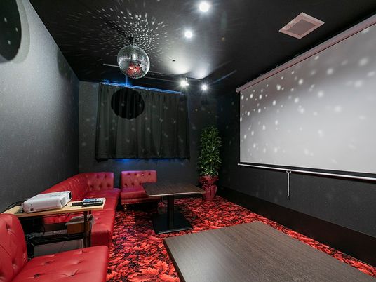 大きなスクリーンが設置された本格的なシアタールームには赤いソファやダークブラウンのテーブルもある。