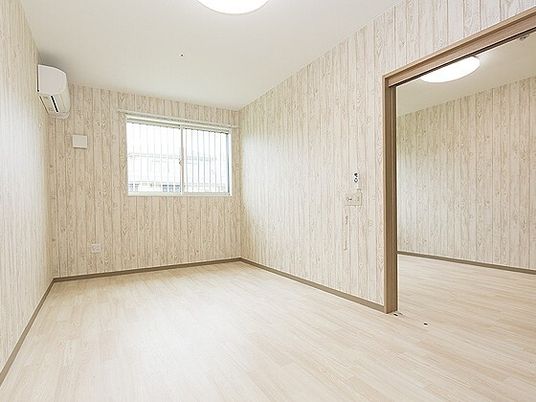 シンプルなフローリングの部屋。家具などは置かれておらず、エアコンが設置され、窓が付いている。