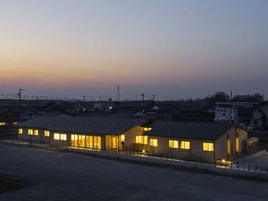 夕暮れに浮かぶグループホームなのはな苑ねむのきの外観。山のない平野に建てられた施設