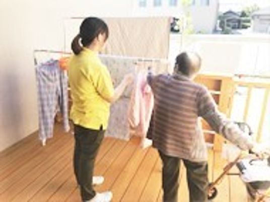 居室を清掃している施設のスタッフと高齢者の様子。生活リハビリの一場面