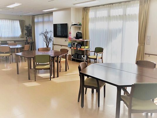 六角形のダイニングテーブルセットが複数置かれた食堂には大きな壁掛けテレビも設置されている。