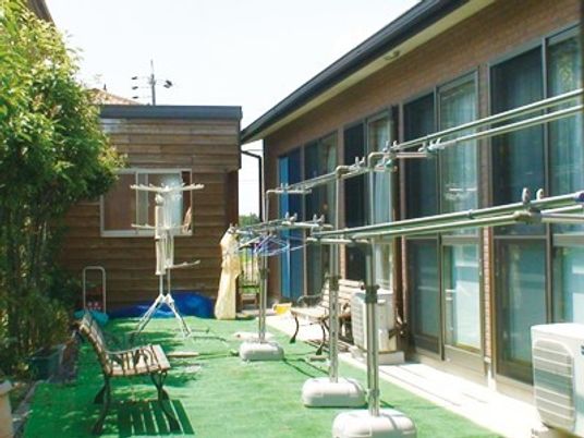 芝生が敷き詰められている小さな中庭の様子。右側に建物と物干し台