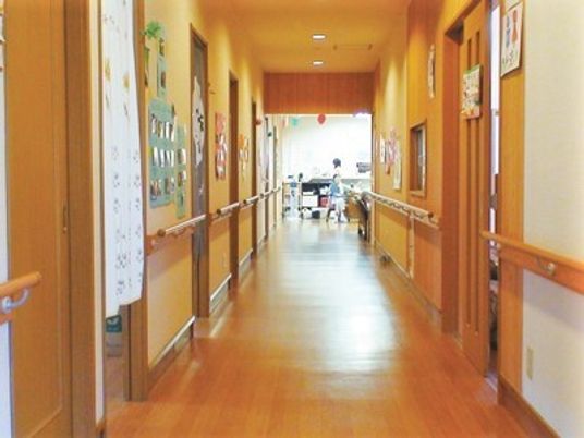 木のぬくもりが感じられる温かみある施設内の内装。両側に個室がある廊下の様子