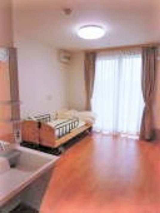 フローリングの居室。大きな窓が付いたシンプルな洋風の部屋には洗面所がある。