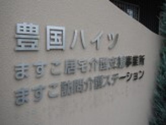 住宅名が書かれた外壁に併設の訪問介護ステーションと居宅介護支援事業所の名前もある。