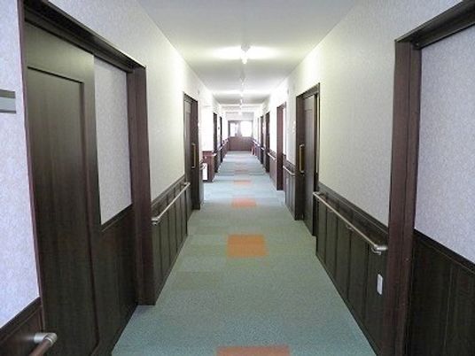 まっすぐな廊下にはダークブラウンの手すりが付き、突き当りには大きな窓がある。居室のドアはすべて引き戸となっている。