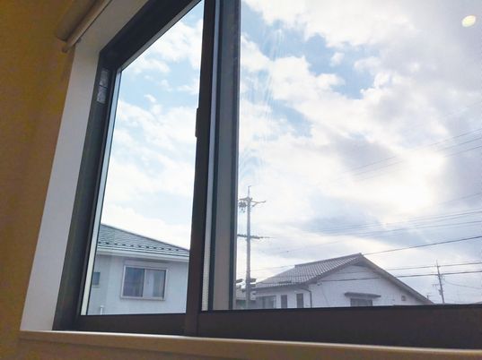 階段の窓からは周辺の景色や空を眺めることができる。空には厚い雲が広がっていて、住宅の屋根部分が見える。