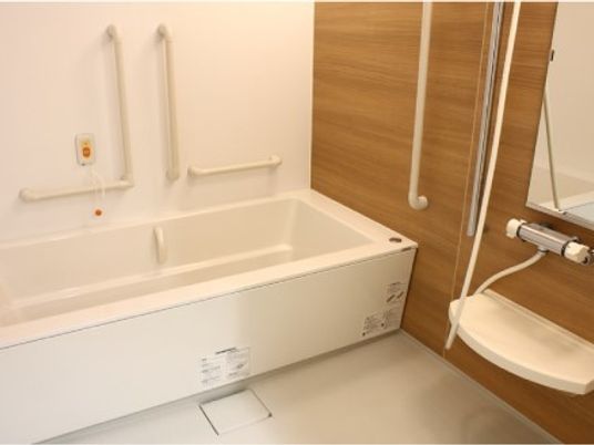 白い浴槽が設置された浴室にはシャワーや手すり、鏡なども設置されている。