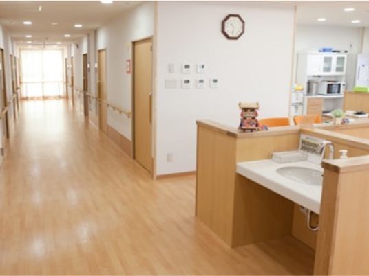 まっすぐな廊下は明るく、突き当りには大きな窓があり、両サイドに居室と手すりがある。