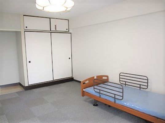 ベッドが置かれた居室はカーペット敷き。押し入れ風の収納スペースもある。