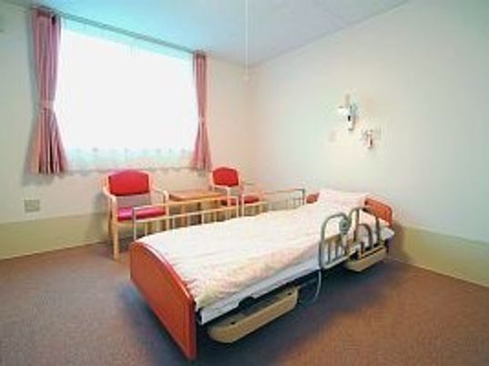 介護士用のベッドが置いてある居室の様子。そばに椅子が二つ置いてあるスペース
