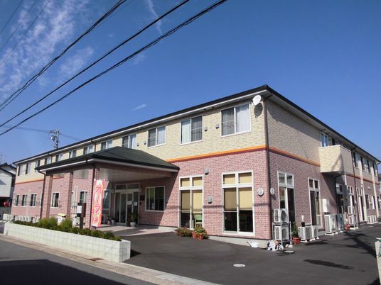 ２階建ての建物。車寄せが付き、レンガ調の外壁が明るい雰囲気。