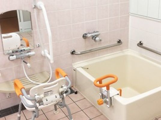 手すりが付いた高齢者用の浴室の様子。シャワーチェアが置いてある様子が写っている