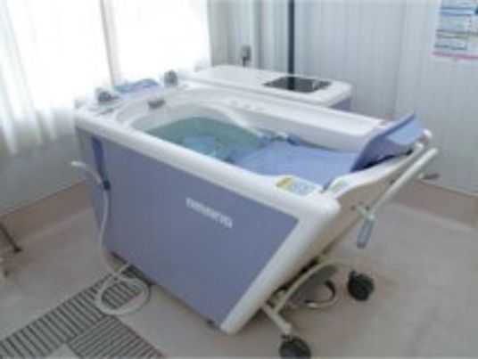 白とブルーの機械浴が設置された浴室。座ったまま浴槽の中に入ることができる。