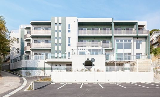 近代的なデザインがめをひく施設の外観デザイン。手前に駐車場スペースがあり、奥に建物が建っている