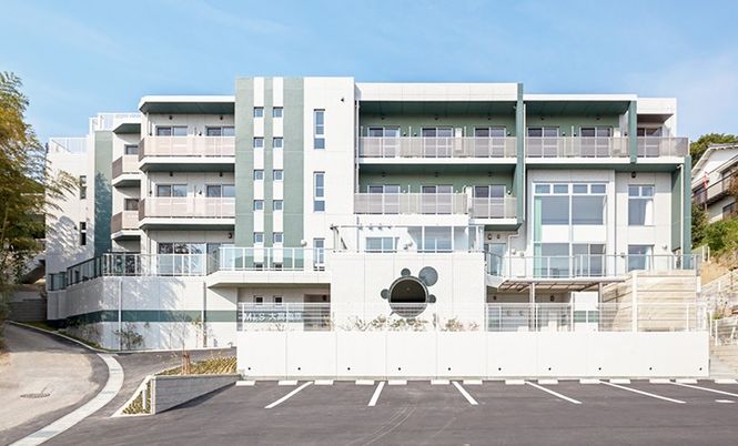 近代的なデザインがめをひく施設の外観デザイン。手前に駐車場スペースがあり、奥に建物が建っている