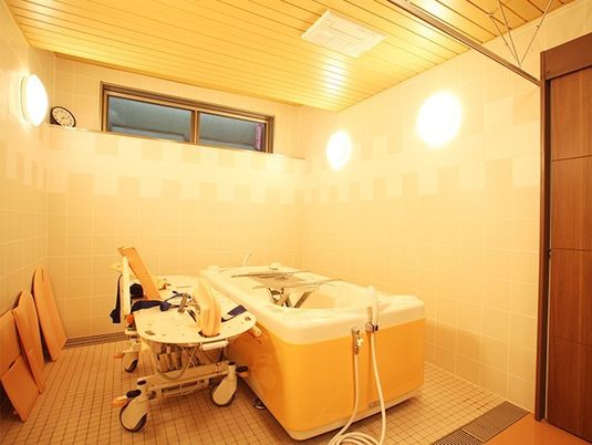 寝たきりの姿勢でも利用できる施設内の介護用浴槽の写真。小さな窓がある浴室内