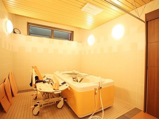 寝たきりの姿勢でも利用できる施設内の介護用浴槽の写真。小さな窓がある浴室内