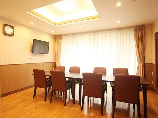 長机と椅子が８脚並んでいる施設内の一室。テレビが置いてある一室の様子