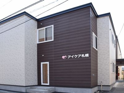 2階建ての建物は一般の賃貸物件のような外観。ブラウンの外壁に白い文字でホーム名が書かれている。