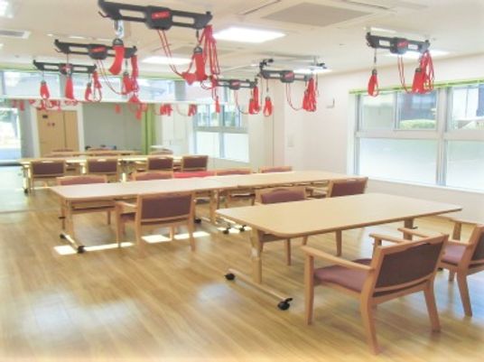 トレーニング機器が並んでいるデイルームの様子。施設内に併設されたデイサービスの写真