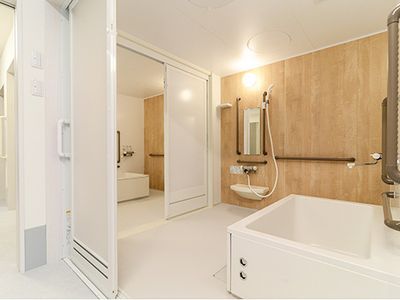 個浴室が二つ並び、間に設置されたドアを通って行き来ができる。壁にはシャワーや手すりも付いている。