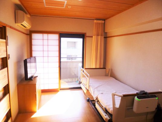 ひとりで部屋でくつろいでいる男性。ホワイトを基調とした部屋で明るい様子が分かる