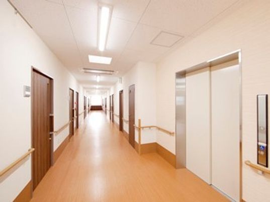 まっすぐな廊下の両サイドには居室があり、全域に手すりが付いている。手前にはエレベーターがある。
