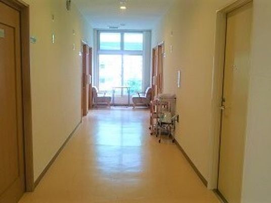 まっすぐな廊下の両サイドに居室のドアがあり、突き当りには大きな窓が付いている。椅子がテーブルもある。