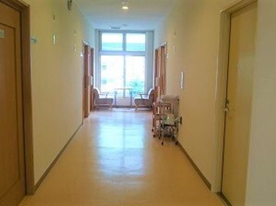 まっすぐな廊下の両サイドに居室のドアがあり、突き当りには大きな窓が付いている。椅子がテーブルもある。