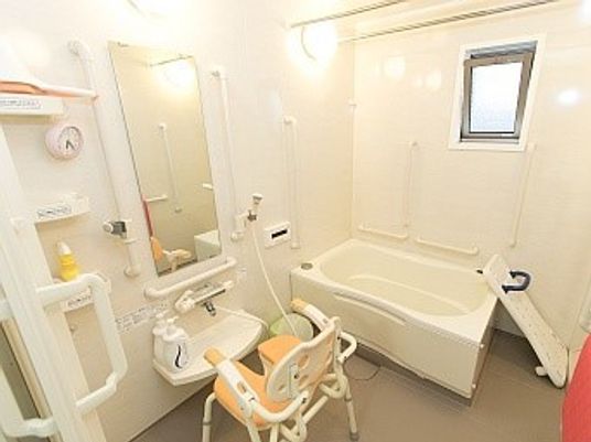 一人用の浴槽が置かれた浴室。手すりやシャワー、バスボードも設置されている。