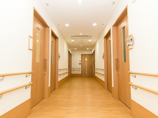 まっすぐな廊下にはブラウンの手すりが付き、居室のドアはすべて引き戸となっている。