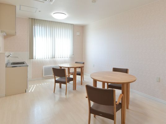 丸いテーブルと椅子が２組並んでいる一室。広めの空間の写真