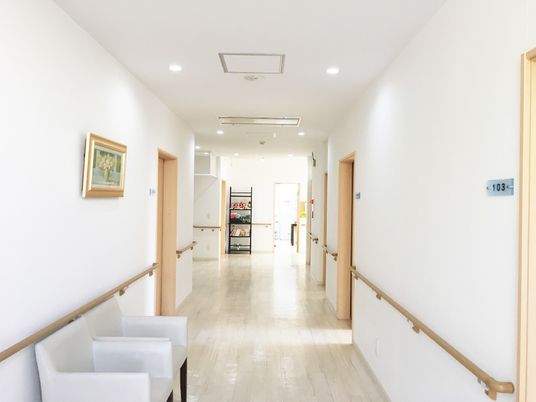 まっすぐに続く廊下に両側に手すりがあり、個室のドアが写っている様子
