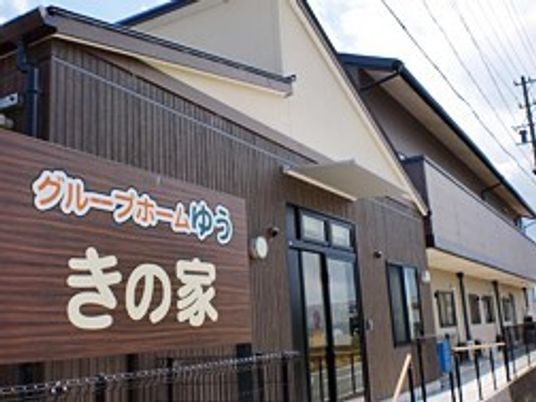 木目調の外壁がアットホームな雰囲気。手前には同じく木目調のホーム看板がある。