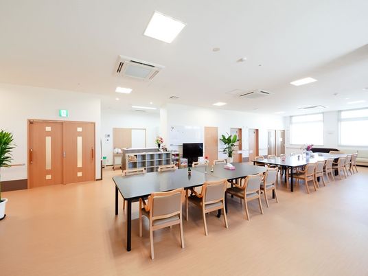 開放的な空間に長机と椅子が複数並んでいる様子。ゆとりをもって配置された家具類