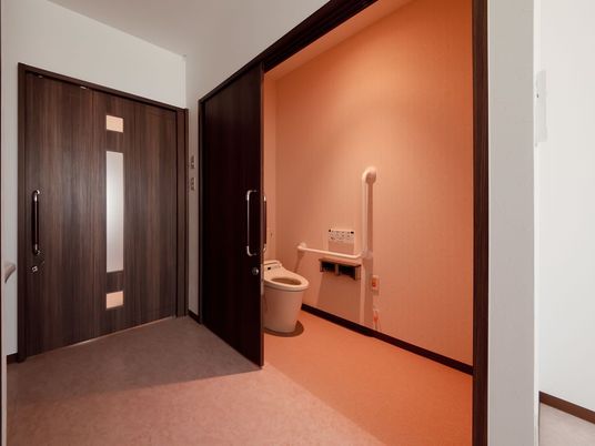 居室の入り口とバリアフリー構造のトイレの様子。エル字型の手すりがついている