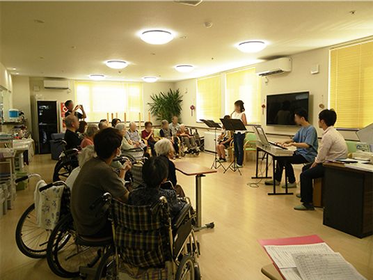 コンサートを楽しむ入居者の様子。前には電子ピアノを弾くボランティアなどがいる。
