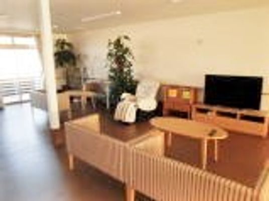 手前に二人掛けソファが二組、奥にテレビが置いてある広めの居室スペースの様子