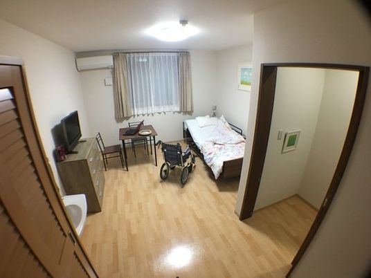 ベッドやレースカーテンが設置された窓がある居室には収納家具もそろい、フローリングで段差が少ない。