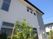 外壁に施設の名前が書かれた2階建ての建物。シンプルな色使いで周辺には緑が植えられている。