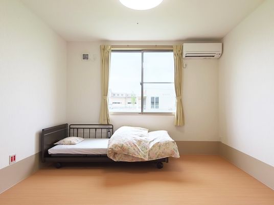 介護用ベッドが置かれたフローリングの居室には大きな窓とエアコンが付き、日当たりも良好。
