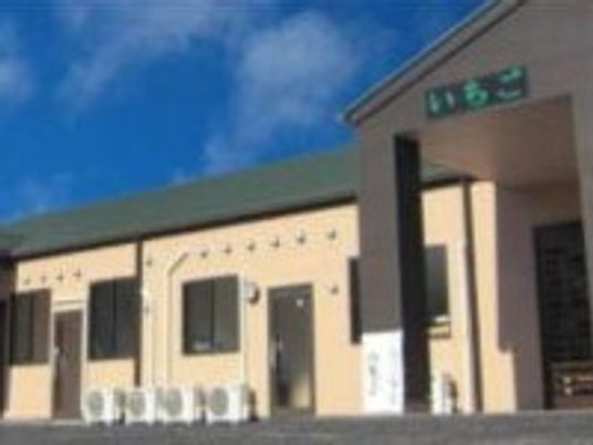 平屋建ての建物の玄関には大きな車寄せが付いていて、外壁はベージュ。日当たりのいい場所に建っている。