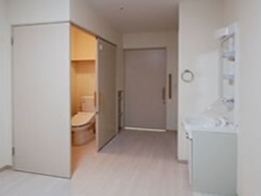 スライド式のドアが設置された広いトイレが付いたフローリングの部屋には洗面所も付いている。