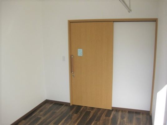 引き戸が付いたフローリングの居室。壁は白く清潔感がある。