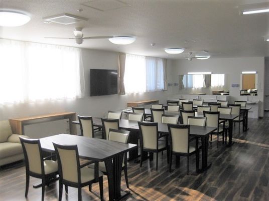 壁掛けテレビが設置された食堂は広く日当たりも良好。奥には洗面所もある。
