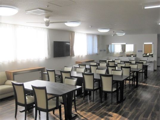壁掛けテレビが設置された食堂は広く日当たりも良好。奥には洗面所もある。