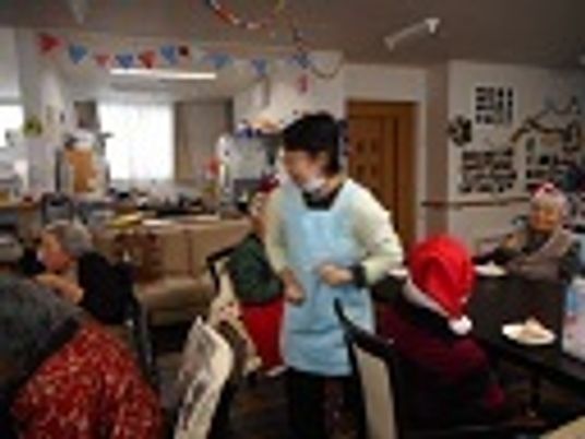 クリスマス会でサンタ帽をかぶった入居者とスタッフが大いに楽しんでいる様子。