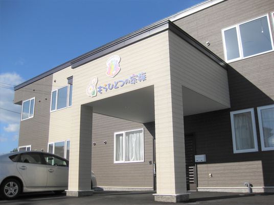 ブラウンを基調とした2階建ての建物。駐車スペースが広く、日がよく当たる。