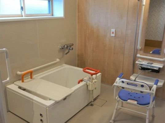 一人用の浴槽が設置されている浴室にはシャワーやシャワーチェア、呼び出しボタンがあり、浴槽にも可動式の手すりなどがある。